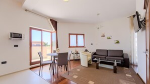 A modern living room with a sofa, dining table, chairs, and a TV. - Lovely apartment in Pula with WiFi (Pula)