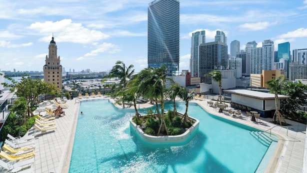 A rooftop pool with lounge chairs, palm trees, and a city skyline in the background. - Luxury unit / amazing view to Downtown/ floor 26th (Miami)
