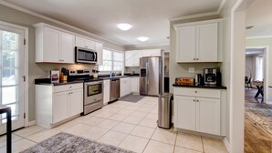 A modern kitchen with white cabinets, stainless steel appliances, and a tiled floor. - Sprawling Updated Ranch with Fireplace on Wimbledon (Thomasville)