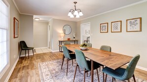 A dining area with a wooden table, four chairs, a chandelier, and framed botanical prints on the wall. - Sprawling Updated Ranch with Fireplace on Wimbledon (Thomasville)