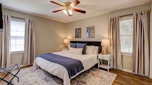 A bedroom with a bed, nightstands, lamps, a ceiling fan, and curtains. - Sprawling Updated Ranch with Fireplace on Wimbledon (Thomasville)