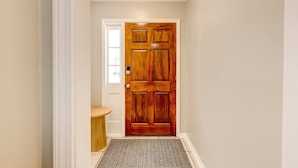 A wooden door with a small window above it, a doormat, and a light-colored wall. - Sprawling Updated Ranch with Fireplace on Wimbledon (Thomasville)