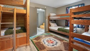 A room with bunk beds, a wooden floor, and a patterned rug. - Walnut Hill Lodge  | Hocking Hills Luxury, Hot Tub (Logan)