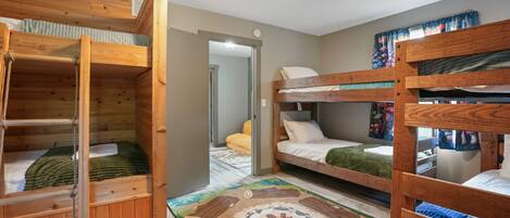 A room with bunk beds, a wooden floor, and a patterned rug.