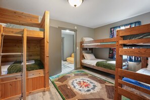 A room with bunk beds, a wooden floor, and a patterned rug.