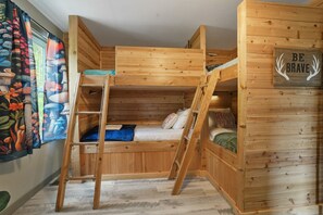 Habitación con literas, una escalera, un cartel que dice 'Be Brave' y una almohada con la frase 'Happy Place'.