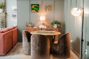 Un salon moderne comprenant un canapé, deux fauteuils, une table avec une lampe et des œuvres d’art décoratives accrochées au mur.