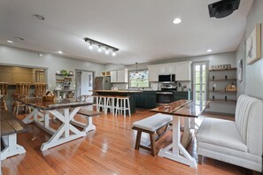 A spacious kitchen with wooden flooring, white cabinetry, and a central island with stools. - Walnut Hill Lodge | Hocking Hills Luxury, Hot Tub (Logan)