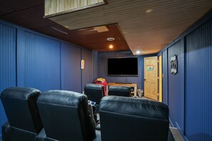 A home theater room with blue walls, a wooden ceiling, and black leather seating. - Walnut Hill Lodge | Hocking Hills Luxury, Hot Tub (Logan)