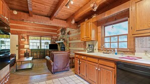 A cozy cabin-style kitchen with wooden cabinets, a dining area with a table and chairs, and a large window with a star decoration.