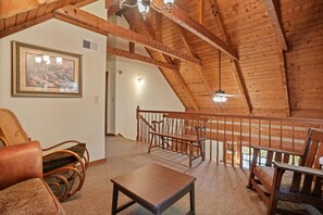 A wooden interior with a high ceiling, a staircase, and a framed picture on the wall.