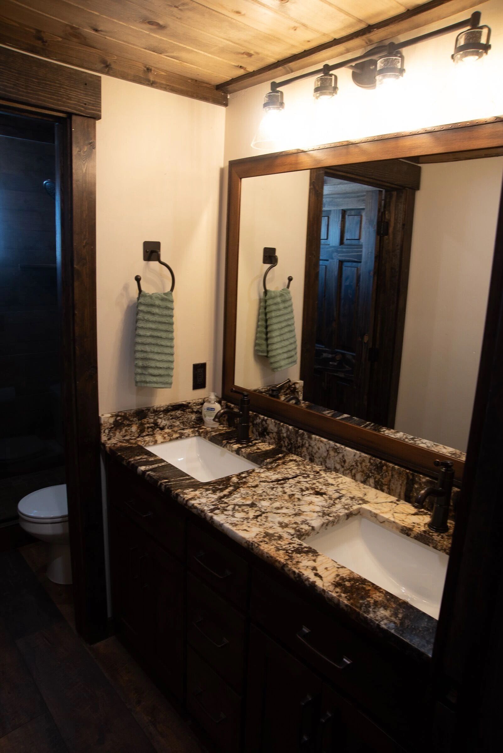Une salle de bain avec un grand miroir, deux lavabos et des meubles en bois.