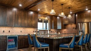 A kitchen with wooden cabinets, a granite countertop, and a bar area with blue bar stools. - All-Season Luxury MTN Retreat @ Lake w/ Hot Tub, Sauna & Near Hiking Trails, YNP (Island Park)