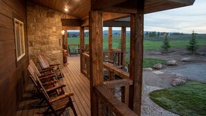 A wooden deck with stone walls and a view of a grassy field. - All-Season Luxury MTN Retreat @ Lake w/ Hot Tub, Sauna & Near Hiking Trails, YNP (Island Park)