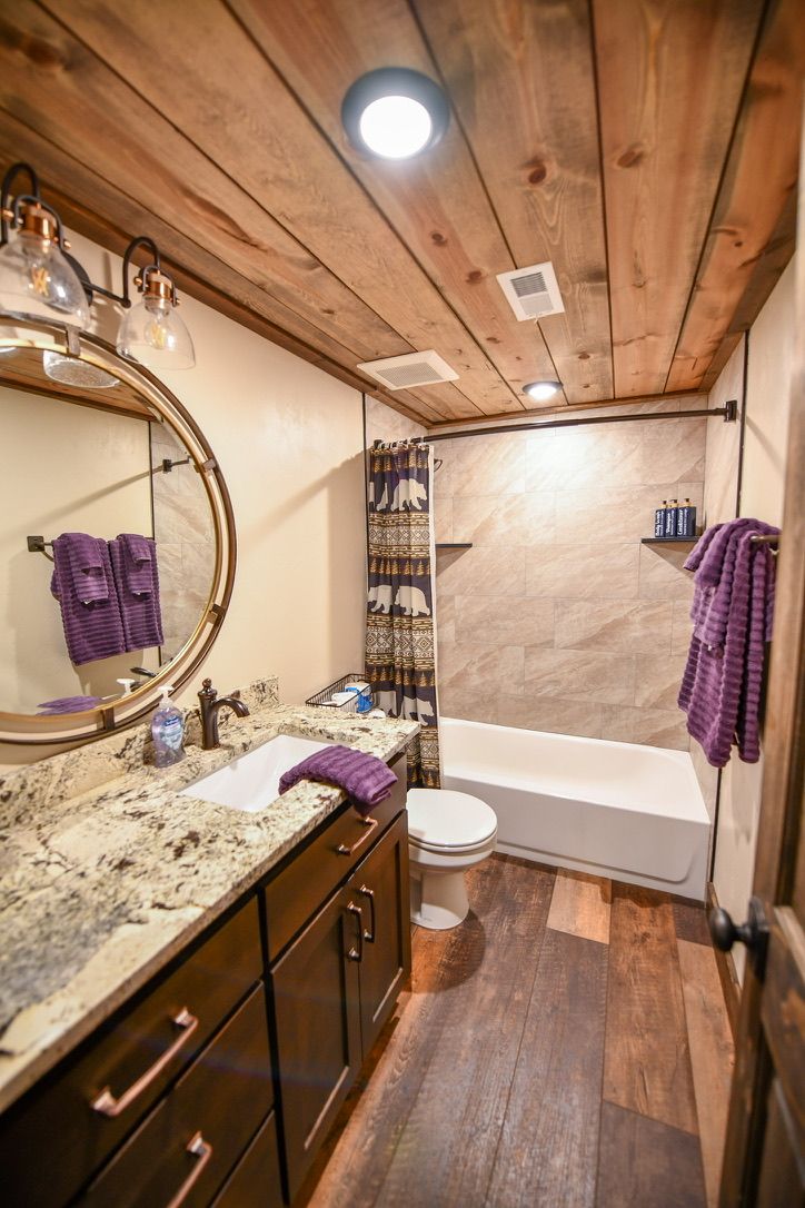 A bathroom with a wooden ceiling, a bathtub, a toilet, and a vanity with a mirror.