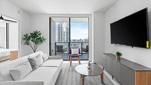 A modern living room with a sofa, a coffee table, and a TV mounted on the wall. - Luxury apartment. Amazing view Downtown MIAMI (Miami)