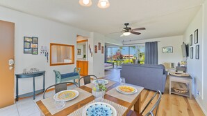 Un comedor con mesa de madera dispuesta para dos, ventilador de techo y vistas al exterior.