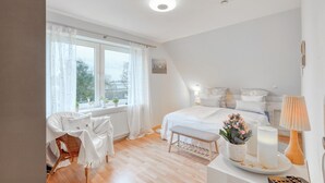 A bedroom with a large bed, a bedside table with a lamp, a chair, and a window with curtains. - Amazing apartment in Höhndorf with WiFi (Höhndorf)