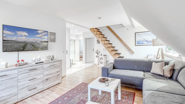 A modern living room with a grey sofa, a white coffee table, and a wooden staircase. - Amazing apartment in Höhndorf with WiFi (Höhndorf)