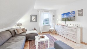 A modern living room with a grey sofa, a white coffee table, and a patterned rug. - Amazing apartment in Höhndorf with WiFi (Höhndorf)