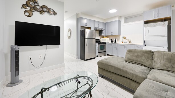 A modern kitchen with grey cabinets, a stainless steel refrigerator, and a built-in oven. - Basement Suite in Vancouver (Vancouver)