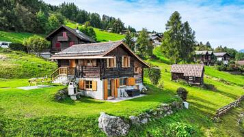 Ein traditionelles Holzchalet mit Steinunterbau, einem Balkon und einer Steinmauer, die das Grundstück umgibt.