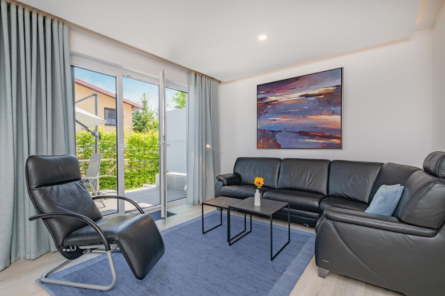 A modern living room with a sofa, a chair, a coffee table, and a painting on the wall.