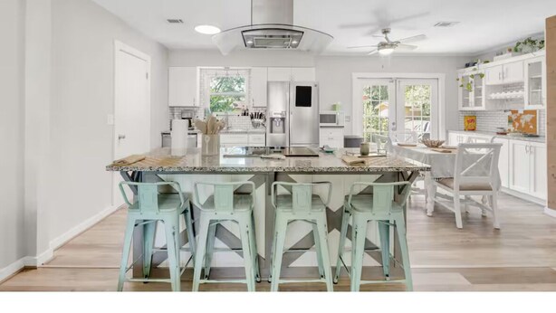 A spacious kitchen with a central island, white cabinetry, and a ceiling fan. - Mermaid Cottage: 5 mi. from beach, fully stocked 3br, grill, deck, bunk bed (Fort Walton Beach)