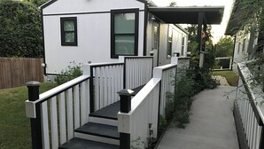 Une maison blanche avec une balustrade noire et des marches menant à un porche abrité.