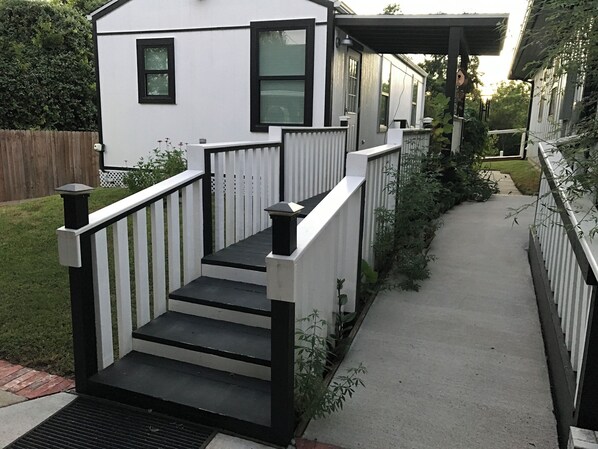 A white house with a black railing and steps leading to a covered porch.
