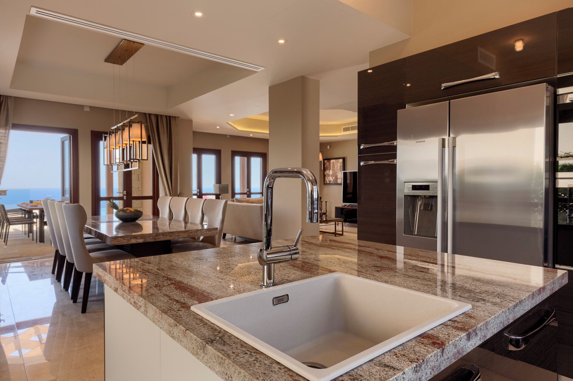 A modern kitchen with a stainless steel refrigerator, a granite countertop, and a built-in sink.