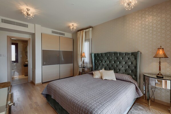 Une chambre à coucher avec un grand lit, une table de chevet, une lampe et une armoire.