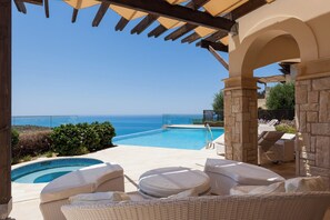 Un espace piscine avec des chaises longues et vue sur l’océan.