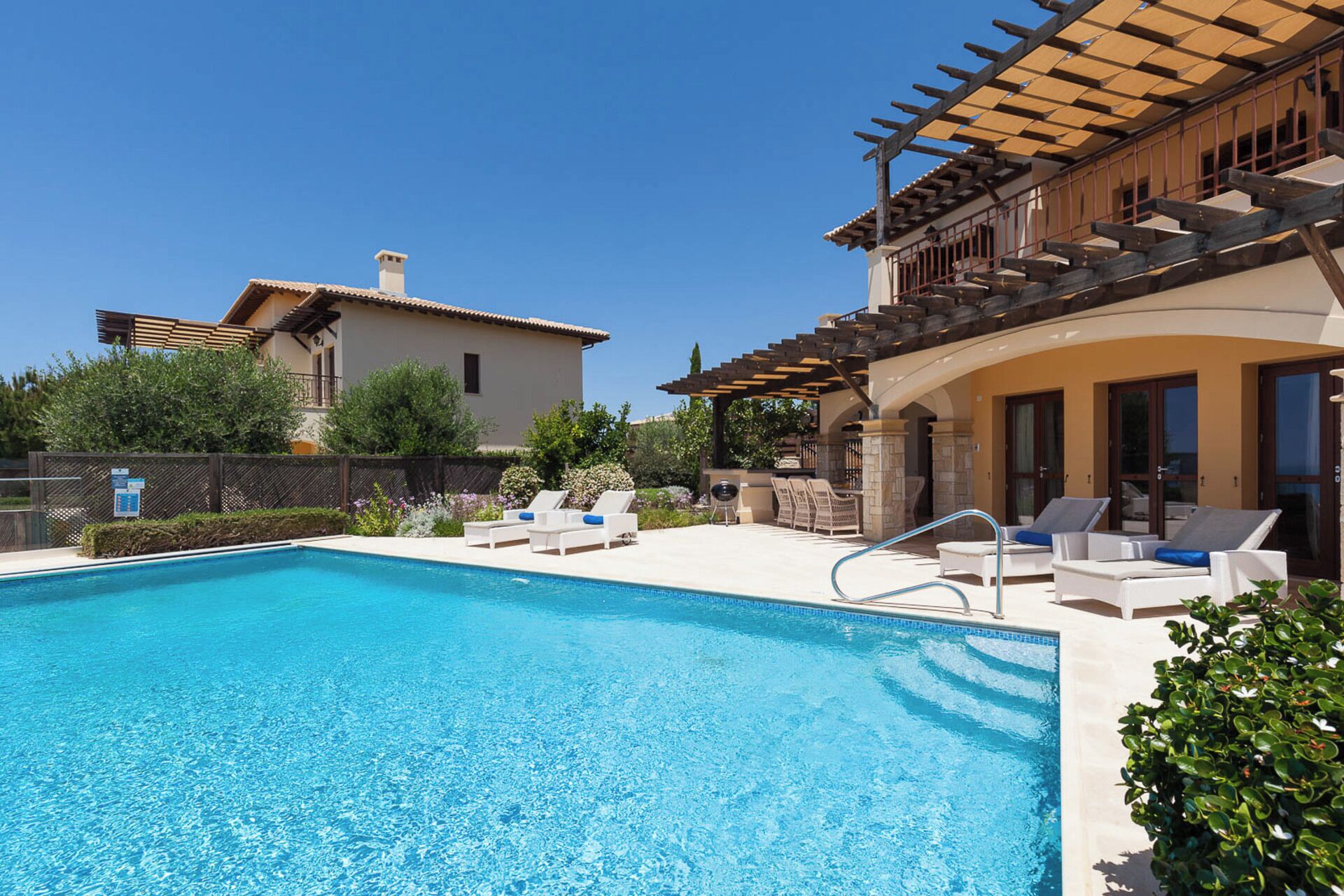 Une piscine avec des chaises longues et une pergola.
