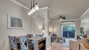 A modern living room with a sofa, coffee table, and a dining area with a table and chairs.