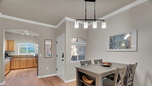 A modern kitchen with wooden cabinets, a dining area with a table and chairs, and a view of the outdoors.