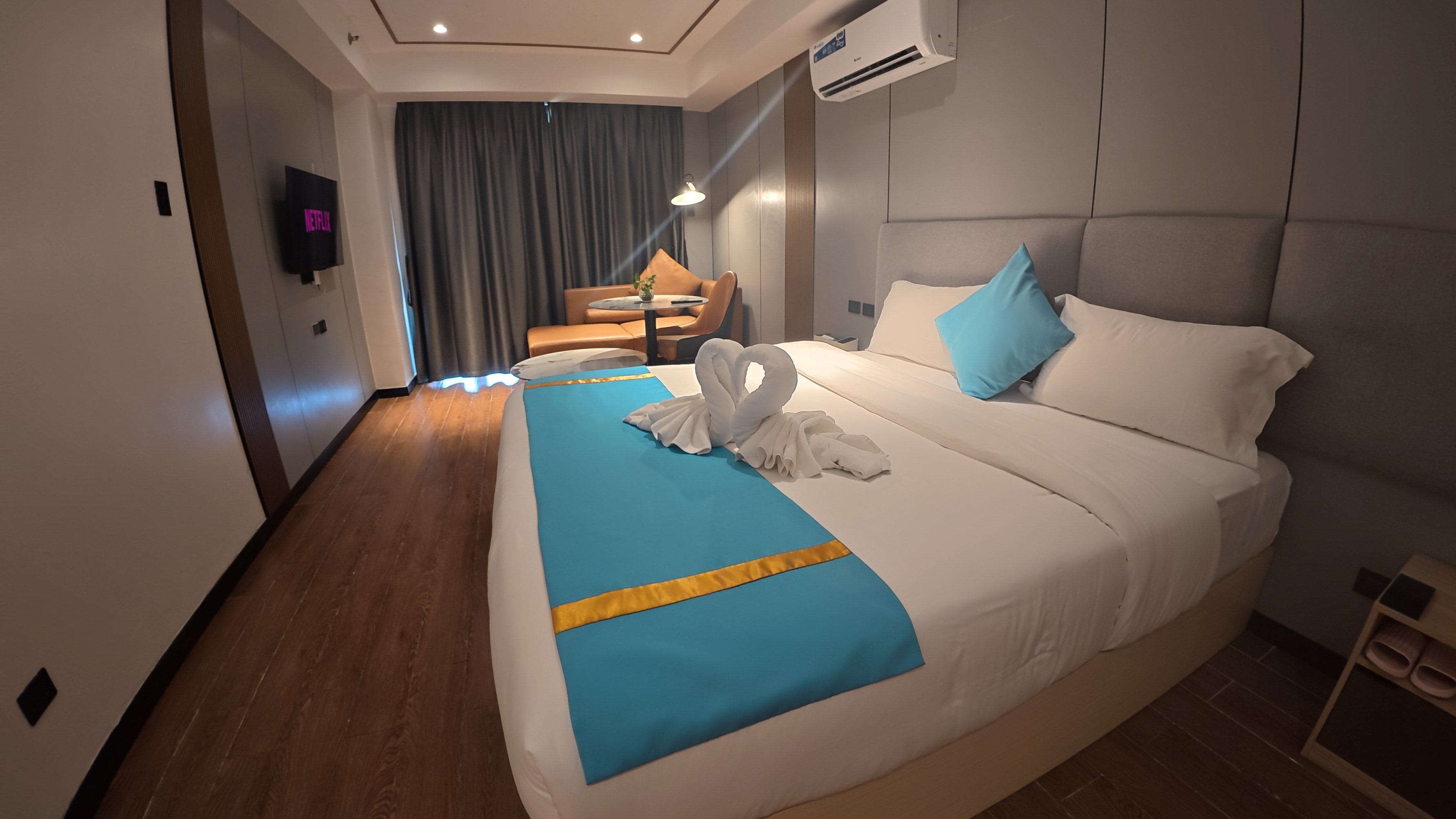 Una habitación de hotel con una cama grande, un televisor de pantalla plana, un escritorio y una silla.