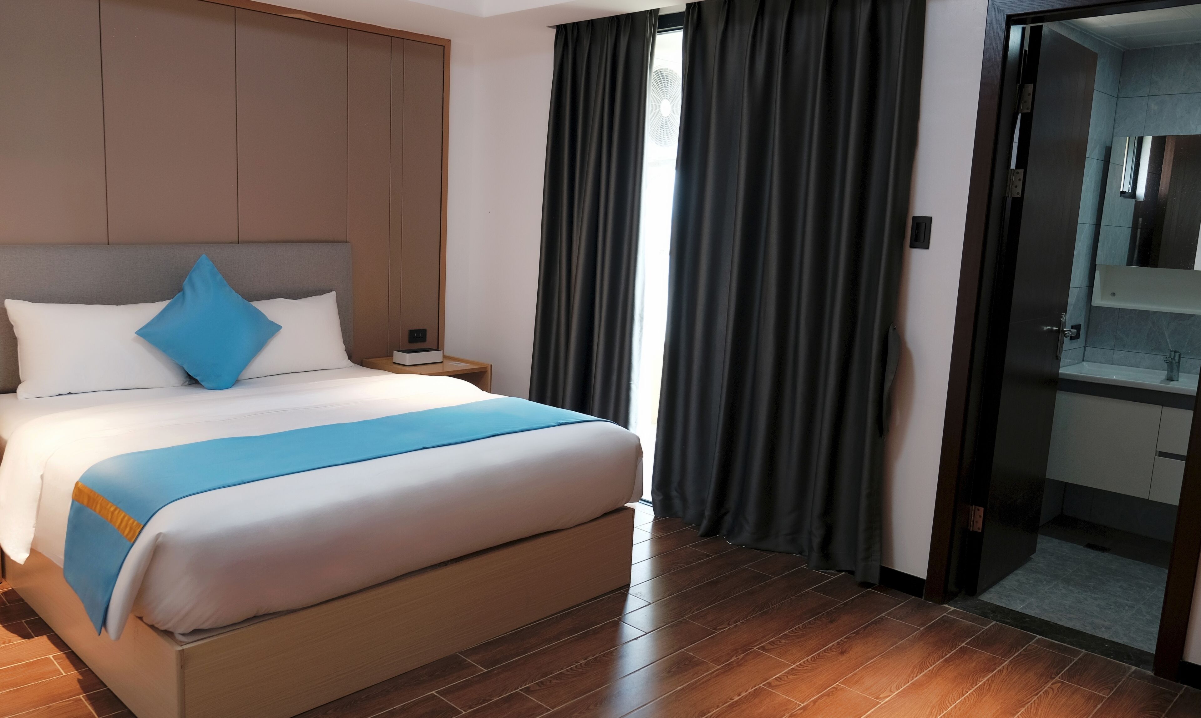 A hotel room with a large bed, a nightstand, a mirror, and a view of the bathroom.