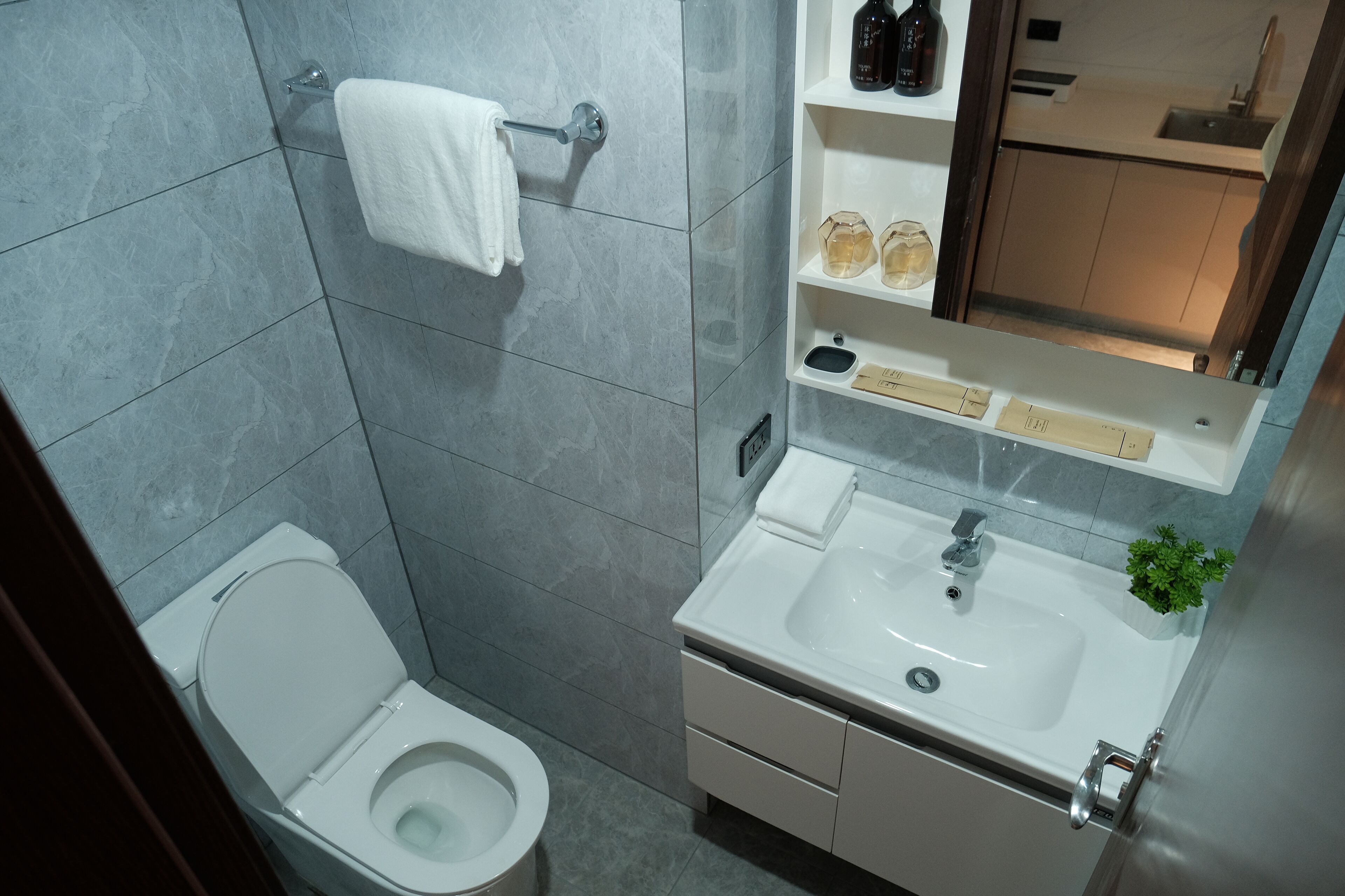 A modern bathroom with a toilet, sink, and mirror.