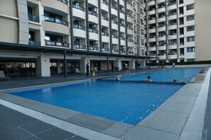 A swimming pool area with a multi-story building in the background. - Golden Seagulls Hotel (Parañaque)