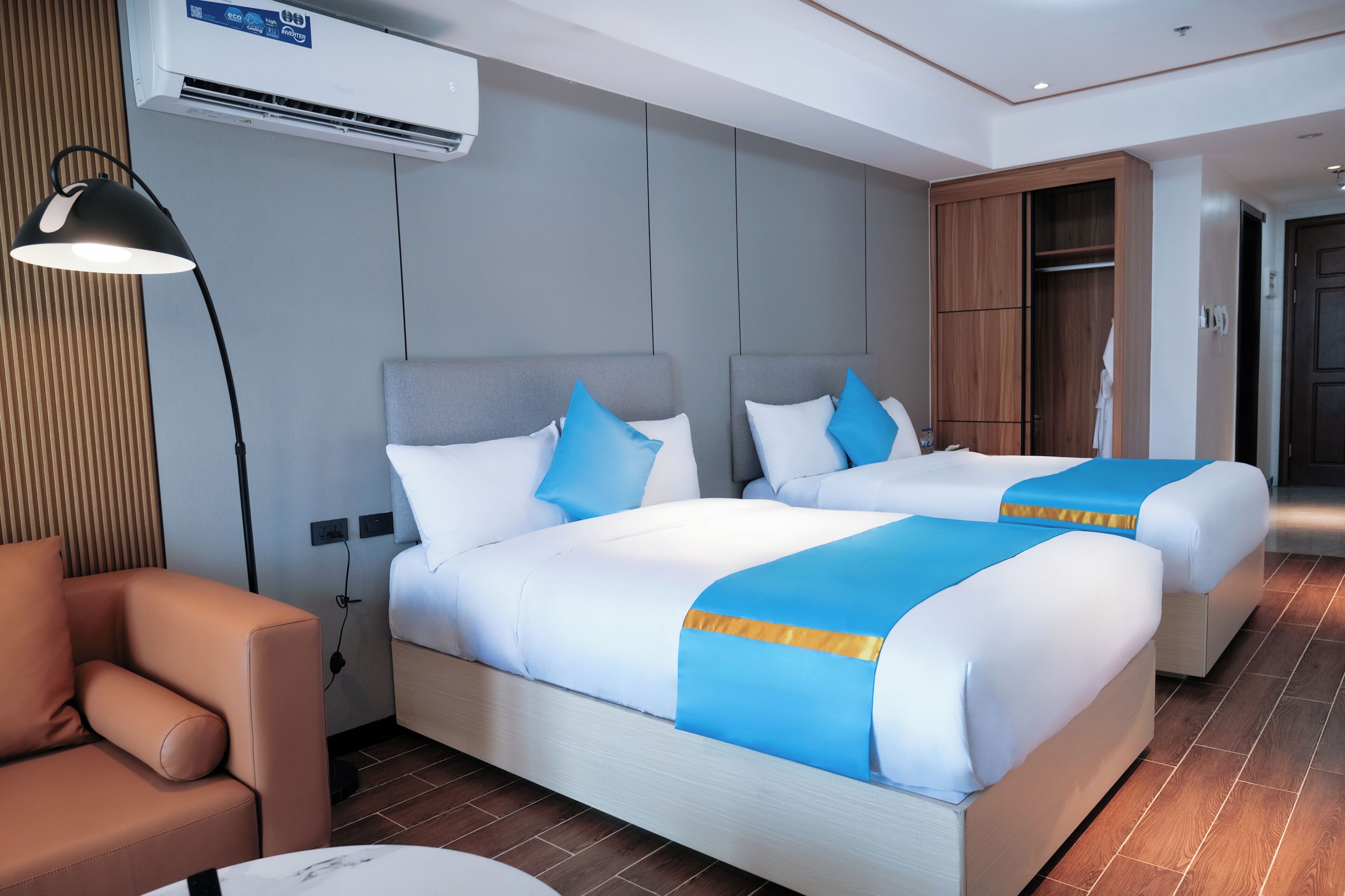 A hotel room with two beds, a sofa, a desk, and a wardrobe.