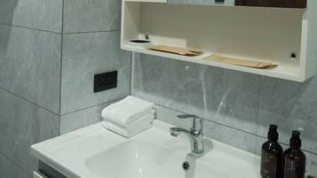 A bathroom with a white sink, a mirror above it, and a wooden cabinet below.