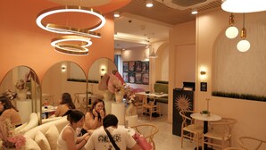 Un interior moderno con mesas y sillas redondas, espejos e iluminación decorativa.