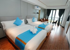 A hotel room with two beds, a seating area, and a large window with a view. - Golden Seagulls Hotel (Parañaque)