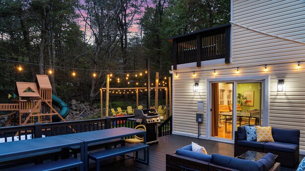 Une terrasse extérieure avec un espace barbecue, des sièges et des guirlandes lumineuses.