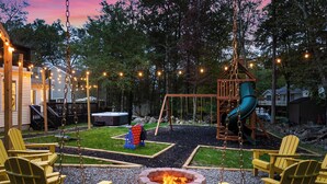 Un jardin avec une balançoire, un toboggan, un foyer extérieur et des sièges pour se détendre en plein air.