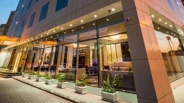 Un hôtel moderne doté d’une façade en verre remarquable, de plusieurs étages et d’un hall d’entrée bien éclairé agrémenté de plantes en pot.