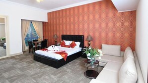 Une chambre d’hôtel avec un grand lit, un canapé, une petite table et un mur décoré d’un motif.