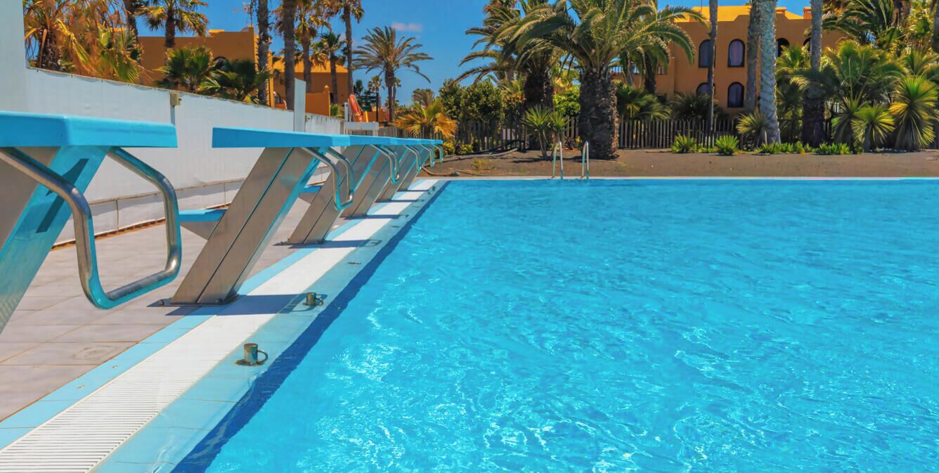 Une piscine à l’eau d’un bleu cristallin, entourée d’un espace aménagé avec des garde-corps en métal et une terrasse carrelée.