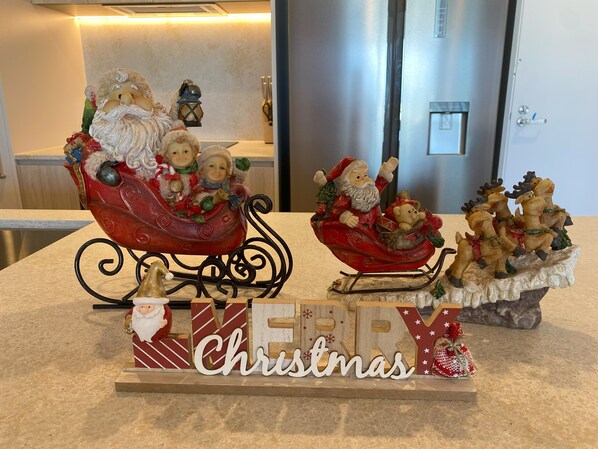 Una encimera de cocina con adornos navideños, incluyendo una figura de Papá Noel en un trineo, renos y un letrero que dice 'Merry Christmas'.